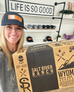 Person holding a Salt River Ranch box with a 'Life is So Good' sign in the background